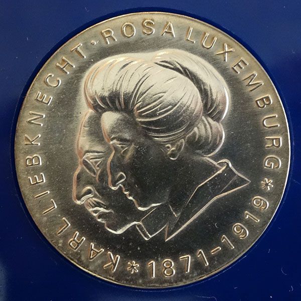 Eine Silbermünze mit Profilen von Rosa Luxemburg und Karl Liebknecht, mit Inschriften.
