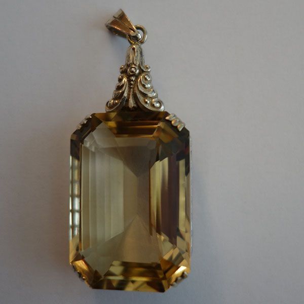 Gold- und Gelbanhänger mit einem großen Edelstein im Rechteckschliff.