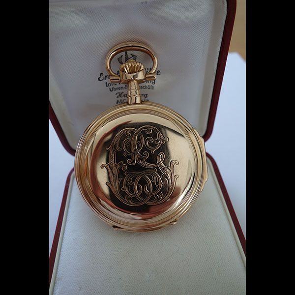 Goldene Taschenuhr mit eingravierten Initialen in einem Präsentationsetui.