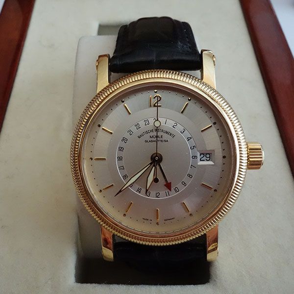 Goldene Armbanduhr mit weißem Zifferblatt, schwarzem Lederarmband und Datumsanzeige.