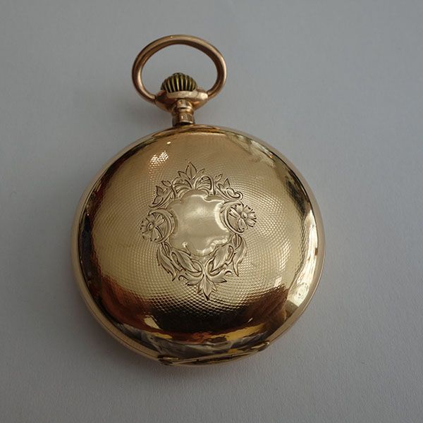 Goldene Taschenuhr mit eingraviertem Blumenmuster auf der Rückseite.