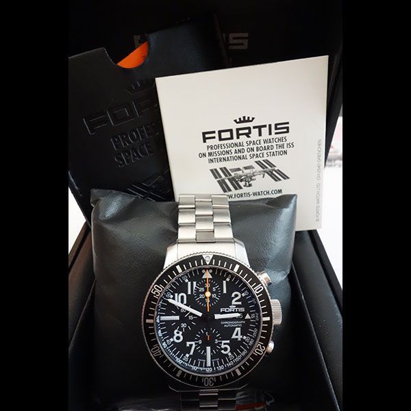 Fortis-Uhr in einer Präsentationsbox mit Unterlagen; Edelstahl, schwarzes Zifferblatt und Armband.