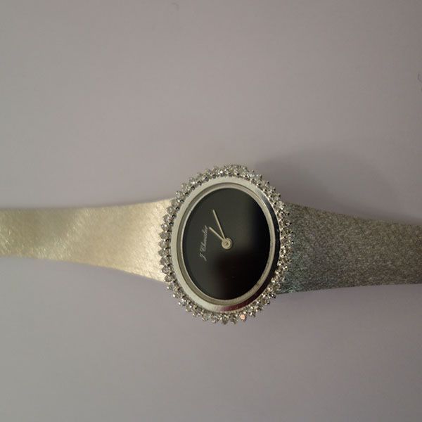 Silberne Armbanduhr mit schwarzem Zifferblatt, diamantbesetzter Lünette und glitzerndem Armband.