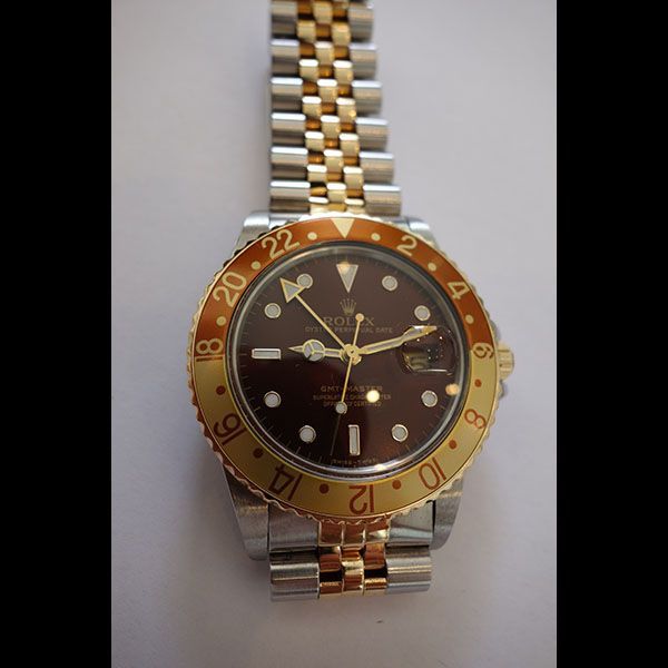 Zweifarbige Rolex GMT-Master-Uhr mit braunem Zifferblatt und goldener Lünette.