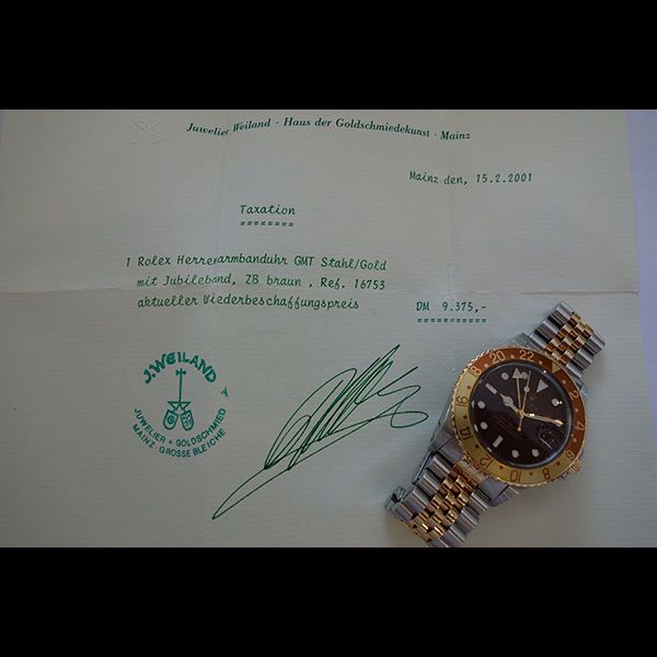 Rolex-Uhr und Quittung mit Unterschrift auf Papier. Die Uhr ist aus Gold und Silber. Der Text ist auf Deutsch.