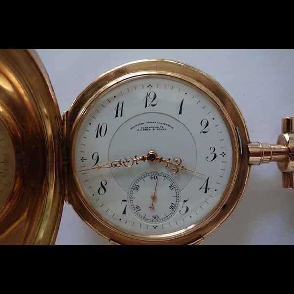 Goldene Taschenuhr mit weißem Zifferblatt, schwarzen Zahlen und kleinem Hilfszifferblatt.