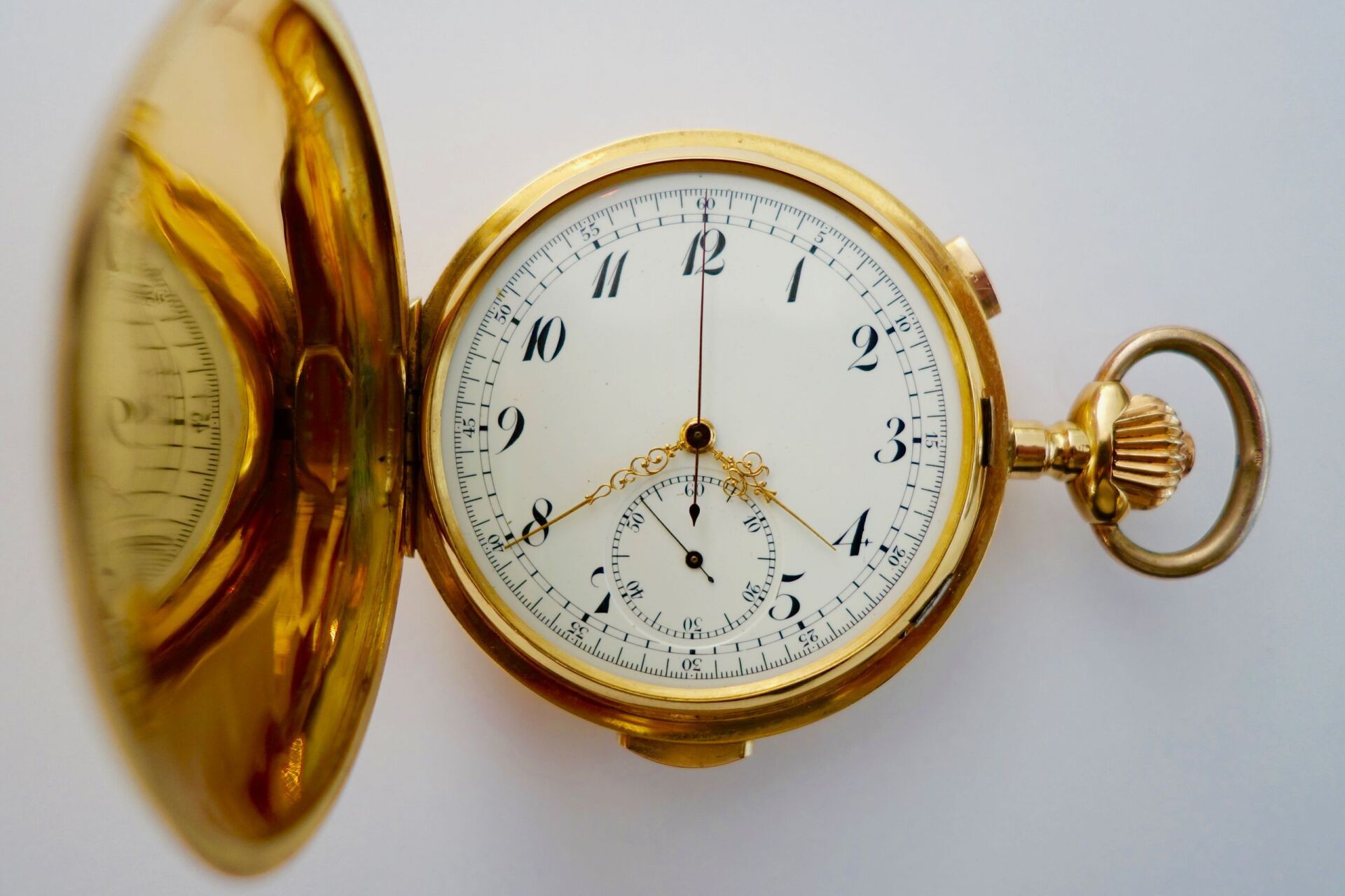 Goldene Taschenuhr mit offenem Deckel, weißem Zifferblatt und Sekundenzeiger.