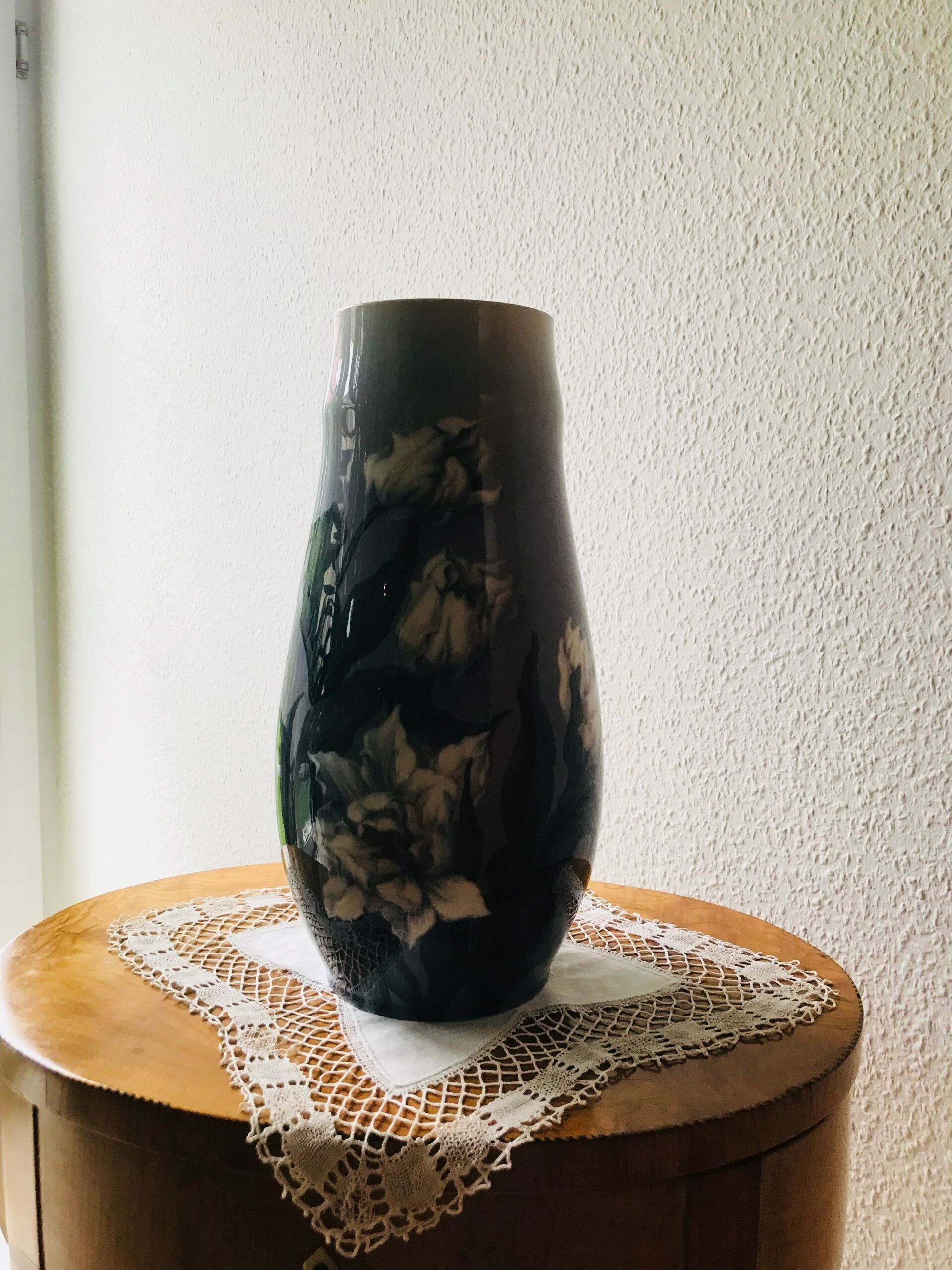 Eine dunkelblaue Vase mit floralen Details.