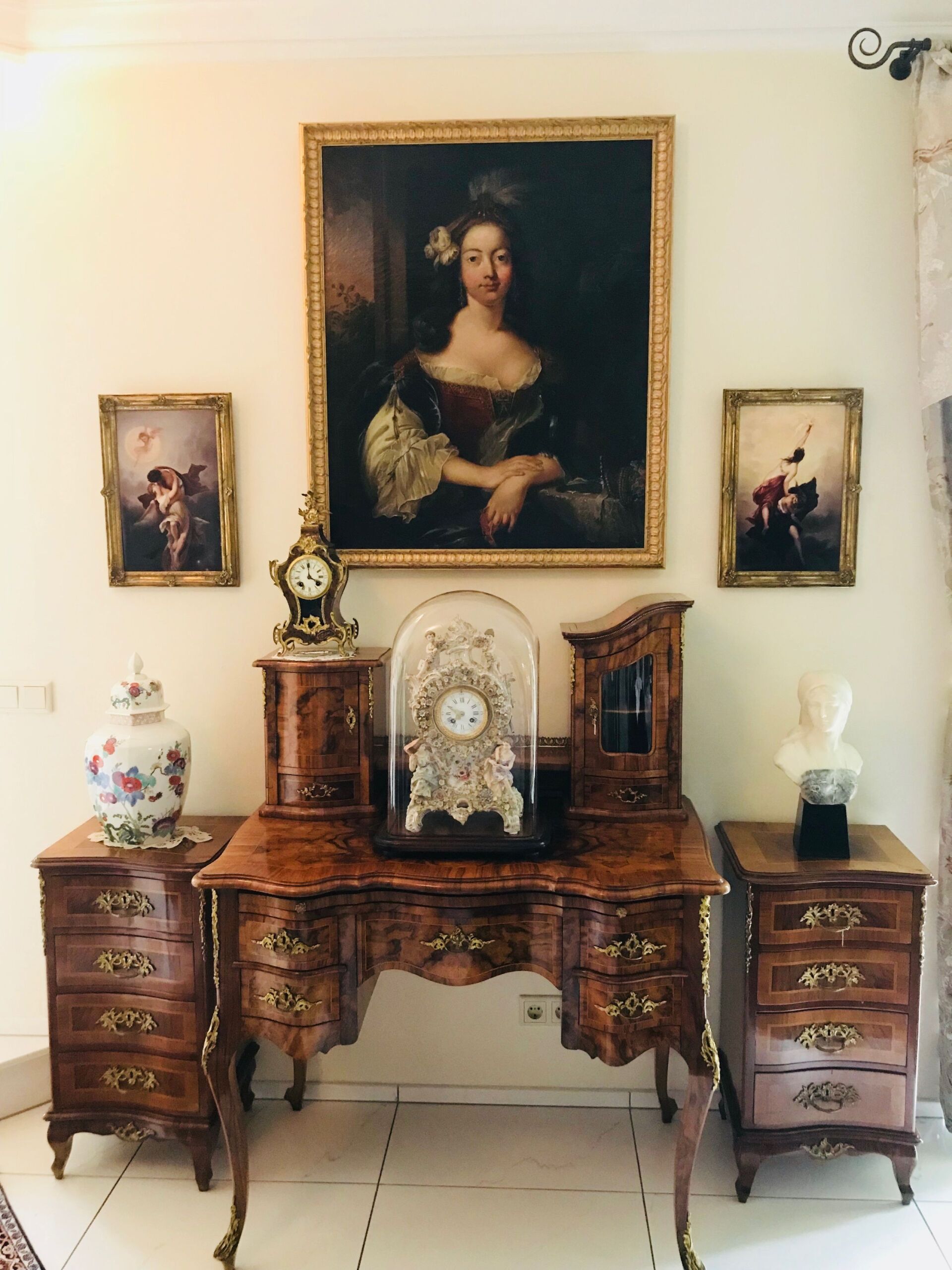 Antiker Schreibtisch mit Gemälden, einer Uhr und Dekorationsgegenständen.