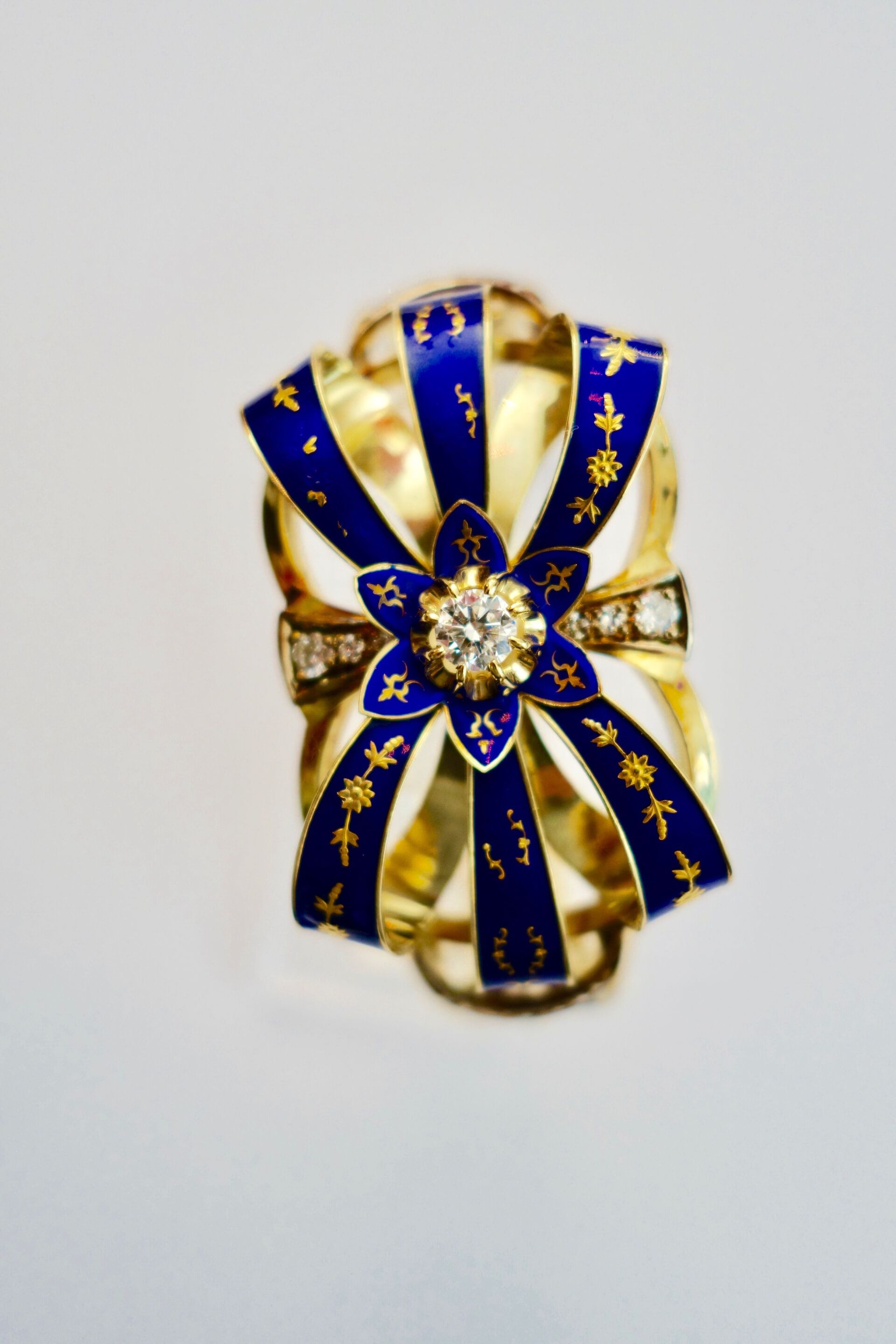 Goldring mit blauem Emaille-Banddesign und zentraler Diamantblume.
