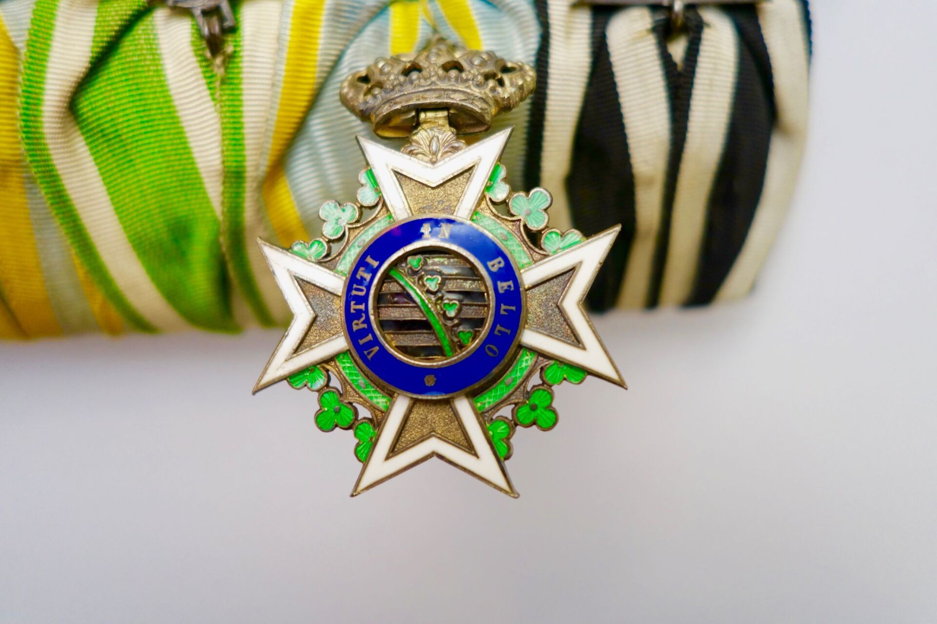 Medaille mit verziertem silbernen Kreuz, Krone und bunt gestreiften Bändern. Text „VIRTU ET BELLO“.