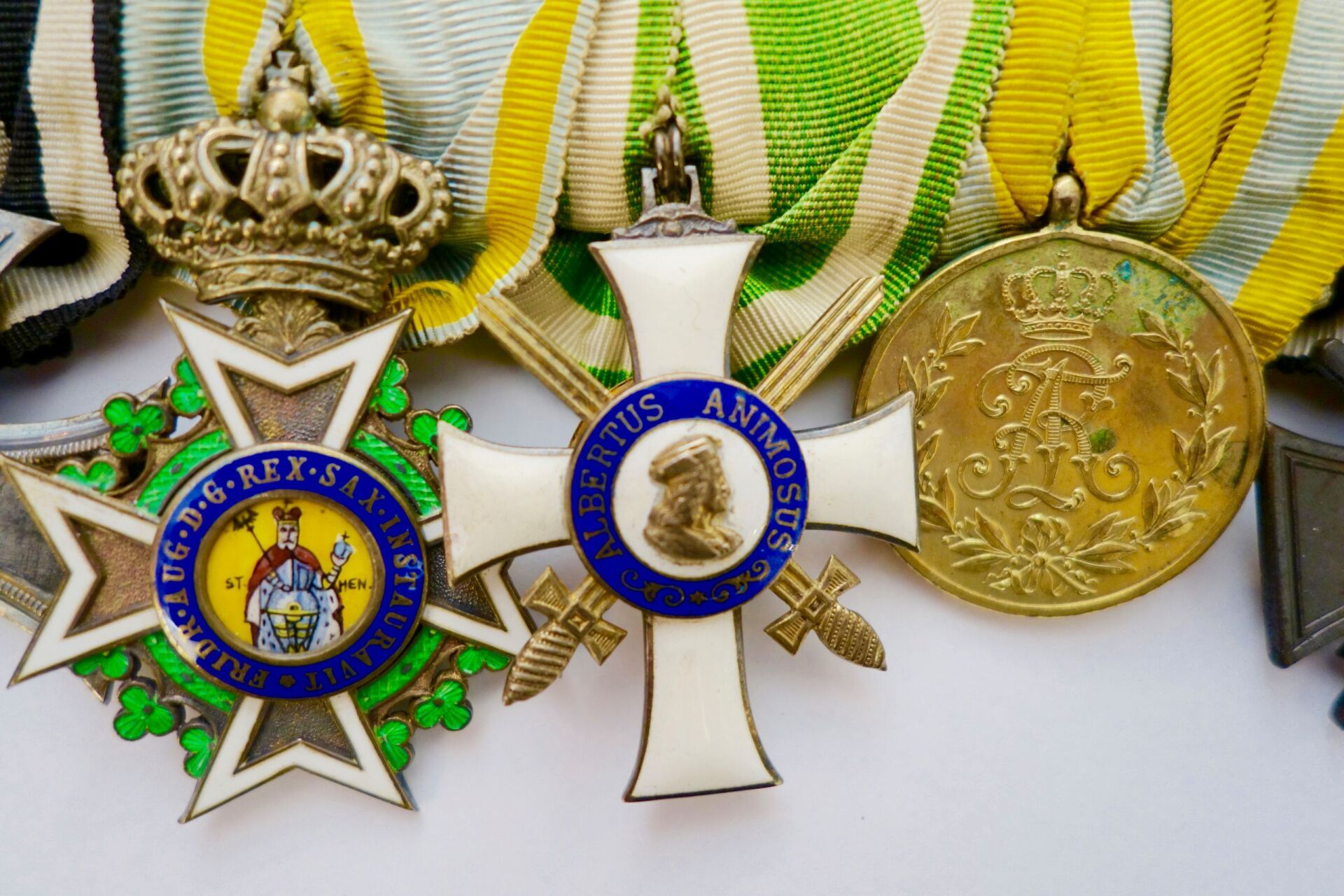 Nahaufnahme von drei antiken Militärmedaillen mit gelben, grünen und weißen Bändern. Gold, Weiß, Blau und Grün.