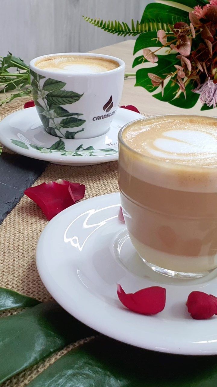 Dos tazas de café están sobre un platillo sobre una mesa.