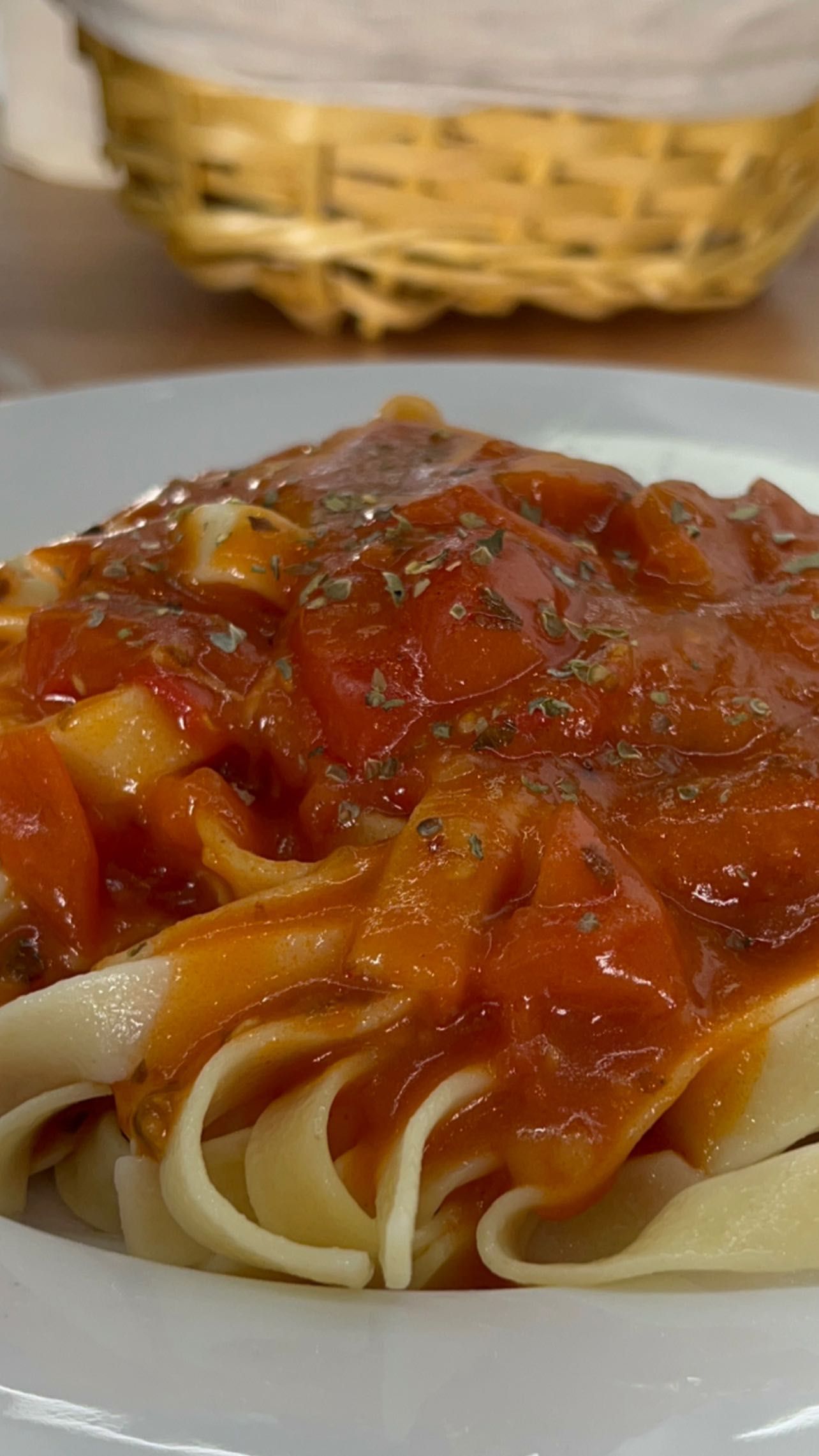 Un plato blanco cubierto con fideos y salsa de tomate.