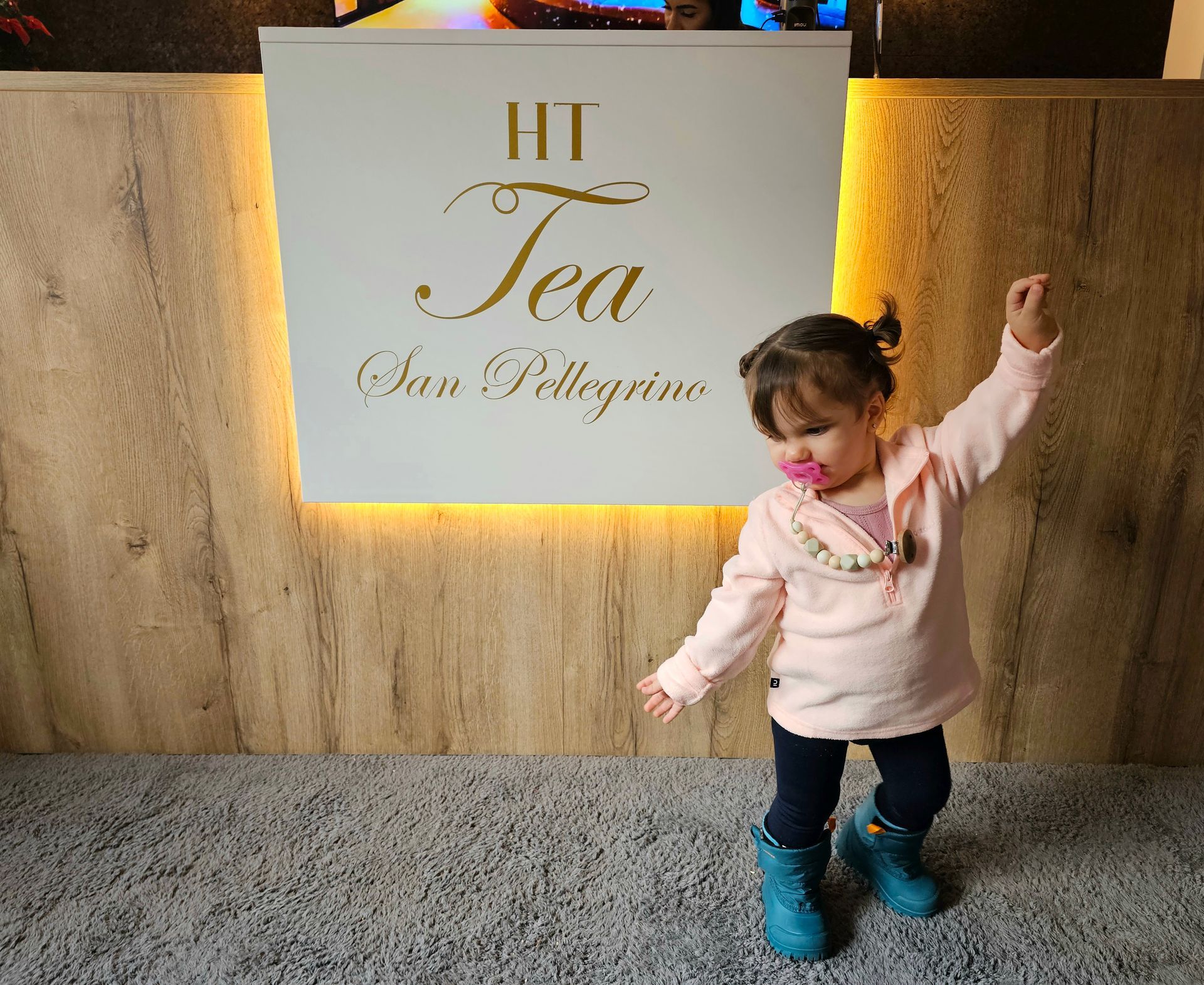 Un bambino vestito di rosa balla vicino a un cartello con la scritta