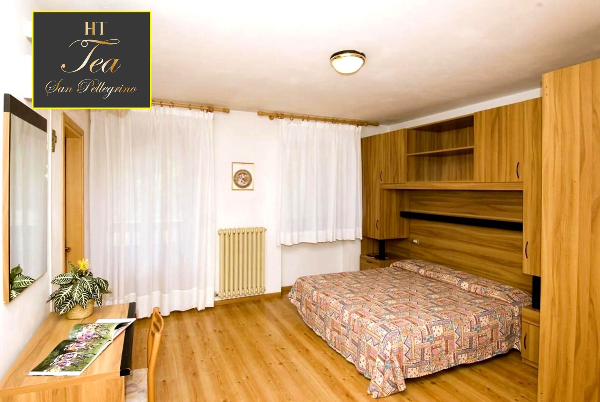 Una camera da letto con letto matrimoniale, mobili in legno e tende bianche.