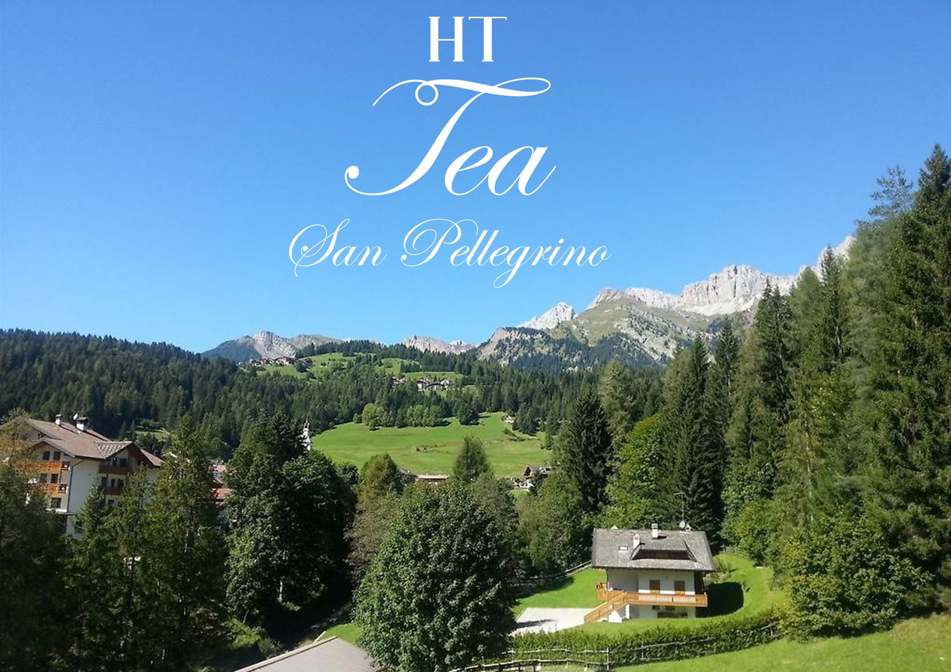 Vista panoramica di San Pellegrino con montagne, alberi, edifici e cielo azzurro e limpido.