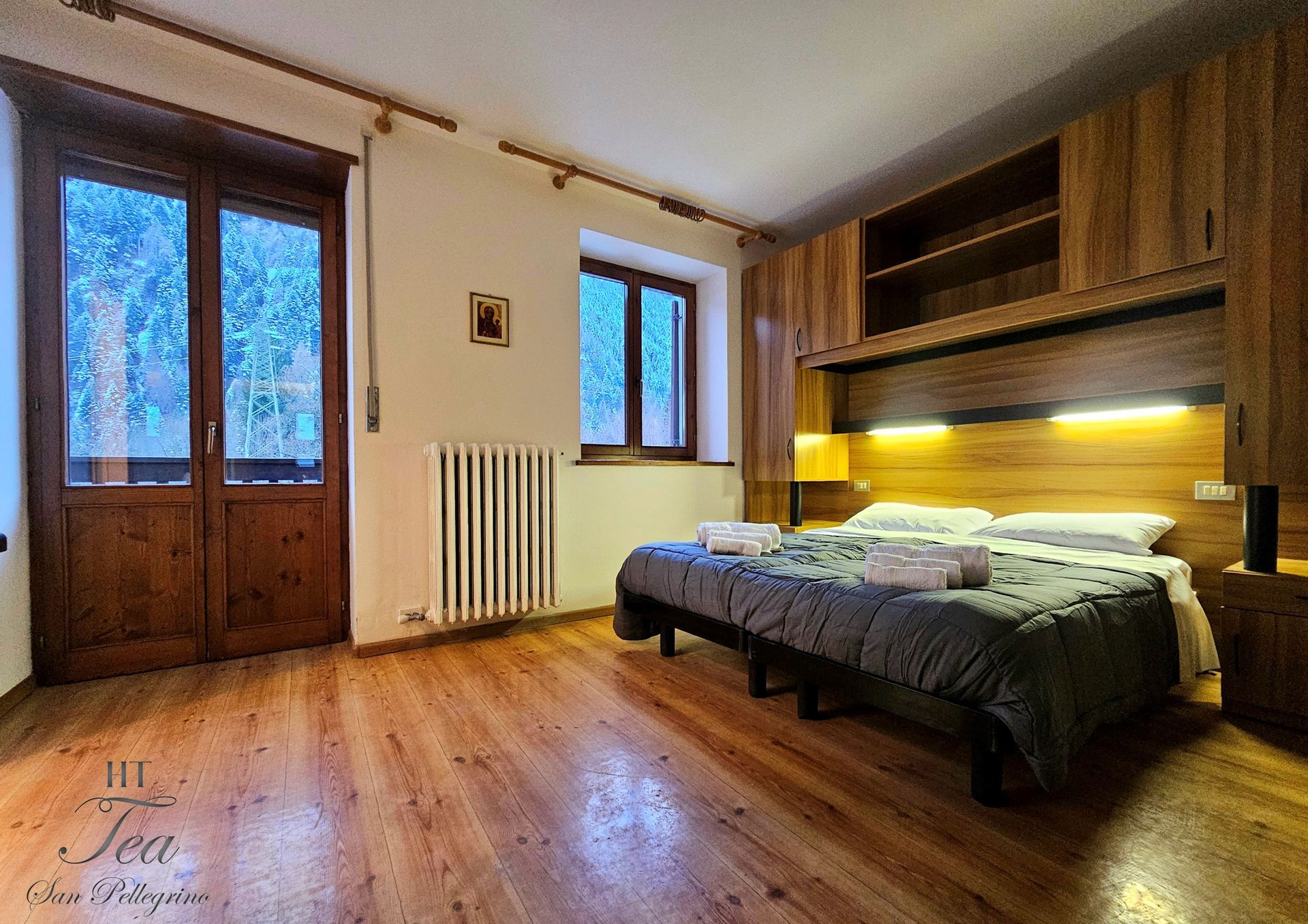 Camera da letto con letto, pavimento in legno e armadi. Sono visibili anche una finestra e una porta.