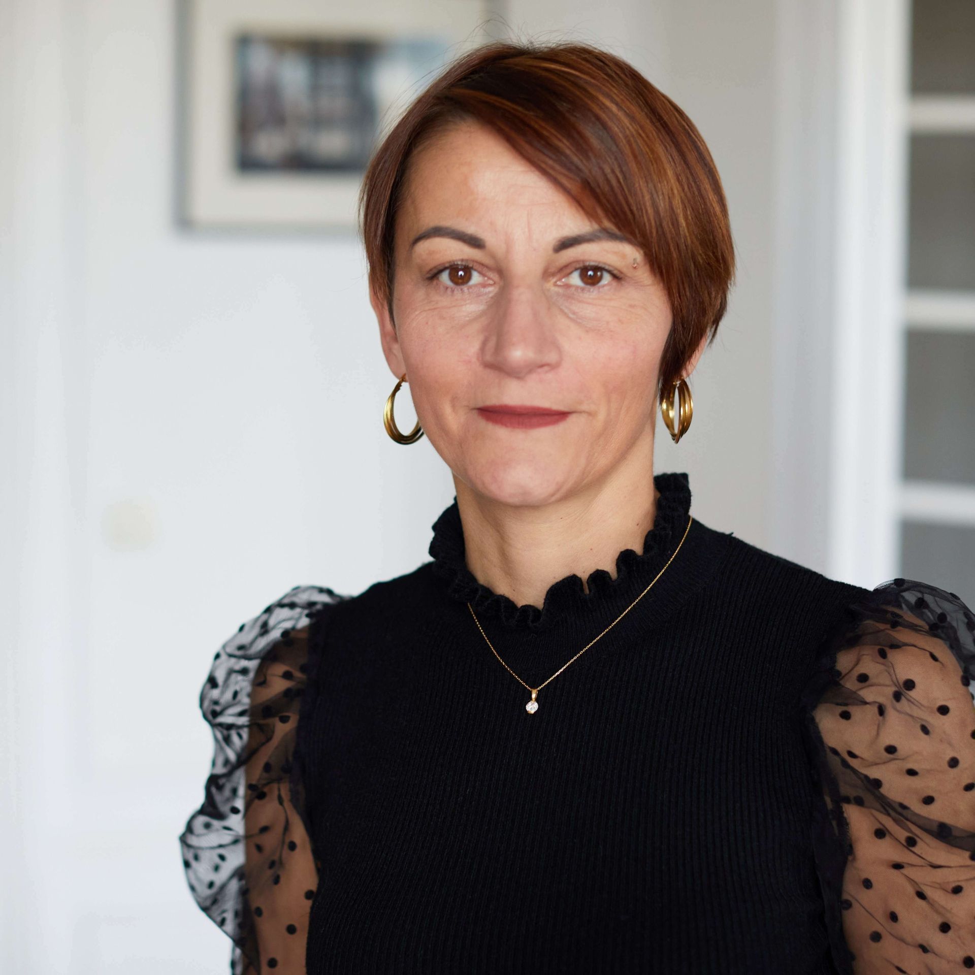 Portrait de la formatrice Françoise Tahiri, debout à l'intérieur sur un fond légèrement flou.
