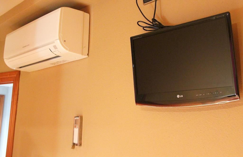 Un televisor de pantalla plana está colgado en una pared al lado de un acondicionador de aire.