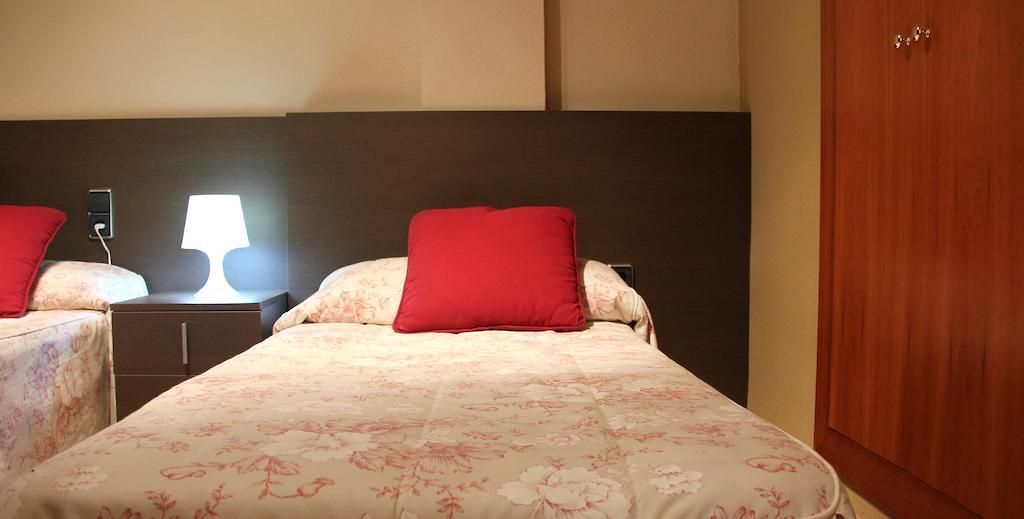 Un dormitorio con dos camas y una lámpara en la mesita de noche.