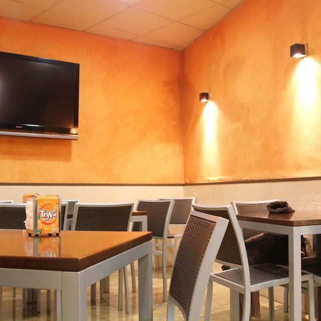 Un restaurante con mesas y sillas y un televisor en la pared.