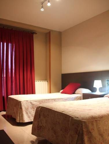 Una habitación de hotel con dos camas y cortinas rojas.