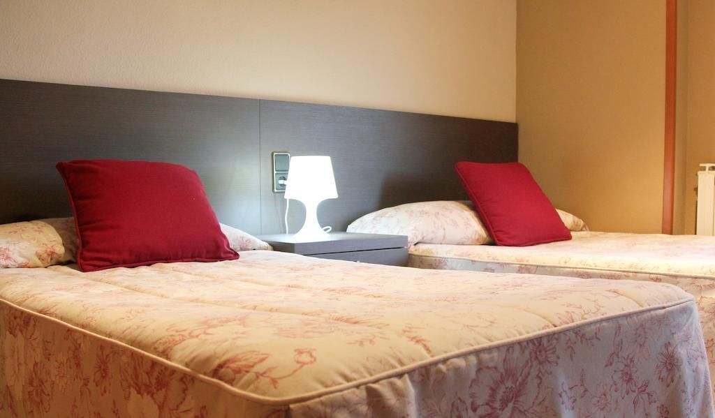 Una habitación de hotel con dos camas y una lámpara.