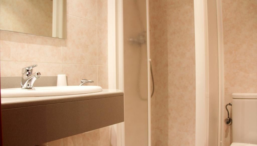 Un baño con inodoro, lavabo, espejo y ducha.