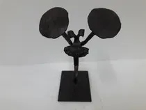 Una estatua negra de una bailarina sobre un soporte sobre una superficie blanca.