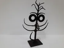 Una escultura negra de un árbol con una cara está sentada sobre una mesa.