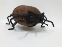 Una hormiga de metal está sentada encima de una roca.