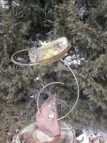 Una escultura está sentada en un tocón de árbol frente a un árbol.
