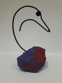 Una escultura de un cisne sentado sobre una roca morada y roja.