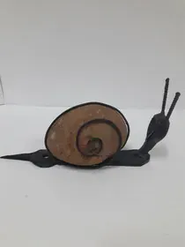 Un pequeño caracol se arrastra sobre una superficie blanca.