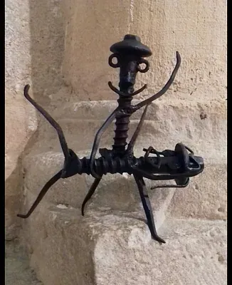 Una escultura de metal de una hormiga sentada sobre una roca.