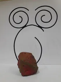 Una escultura de un remolino y una roca sobre una superficie blanca.