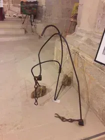 Un objeto de metal está en el suelo al lado de una pared de piedra.
