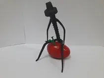 Una estatua de un hombre de pie junto a un tomate sobre una mesa.