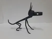 Una escultura de metal negro de un perro está sentado sobre una superficie blanca.