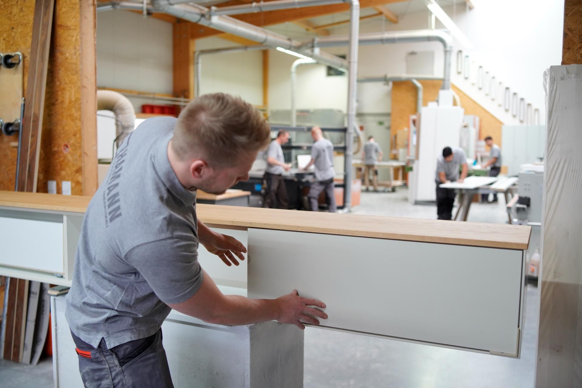 Ein Mann schleift in einer Werkstatt ein individuelles Möbelstück.