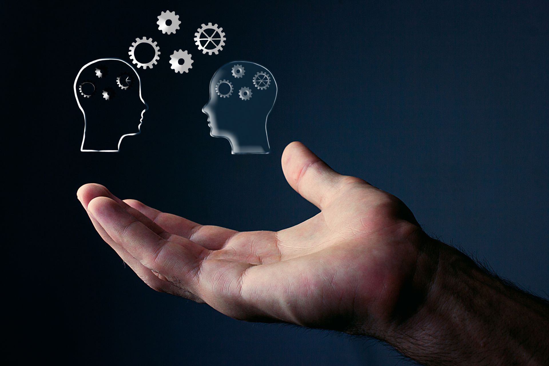 Main tenant des contours de tête transparents avec des engrenages, représentant des idées et des processus de pensée.