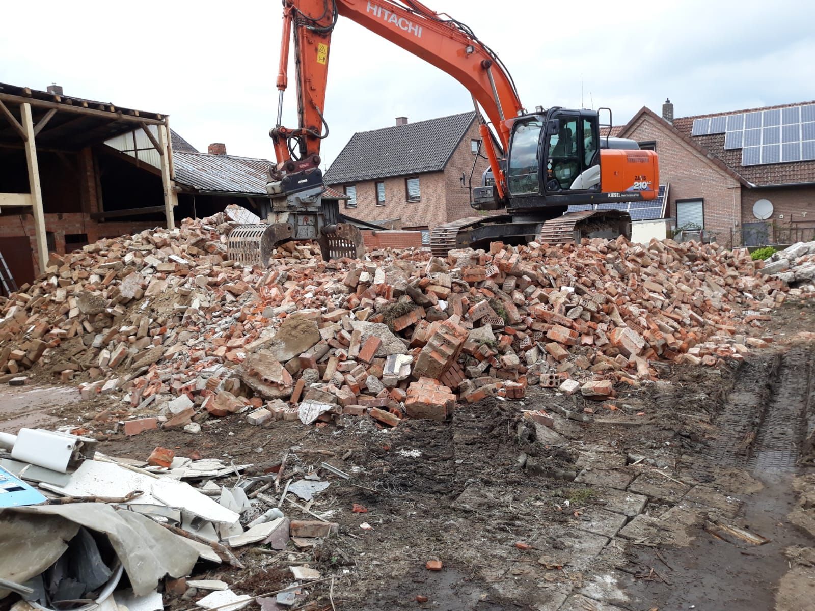 Metallbaggerschaufeln, im Hintergrund ein funktionierender Bagger auf einer Baustelle an einem sonnigen Tag.