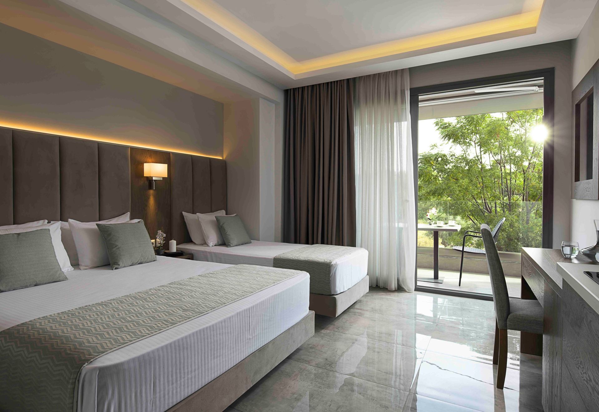 Ein modernes Hotelzimmer mit zwei Betten, grauen Polstermöbeln, Marmorboden und Balkonblick auf üppig grüne Bäume.