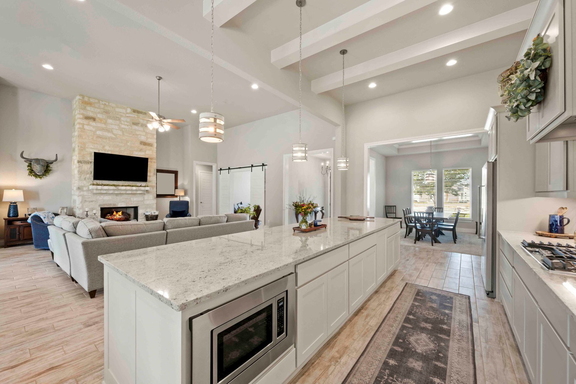 Eine helle, offene Küche mit Marmorinsel, Edelstahl-Mikrowelle und Blick auf ein geräumiges Wohnzimmer.