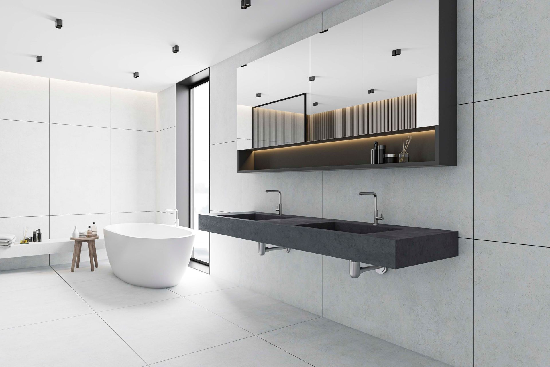 Ein Badezimmer mit weißer Badewanne, einem dunkelgrauen, schwebenden Doppelwaschtisch und einem großen, beleuchteten Spiegel.
