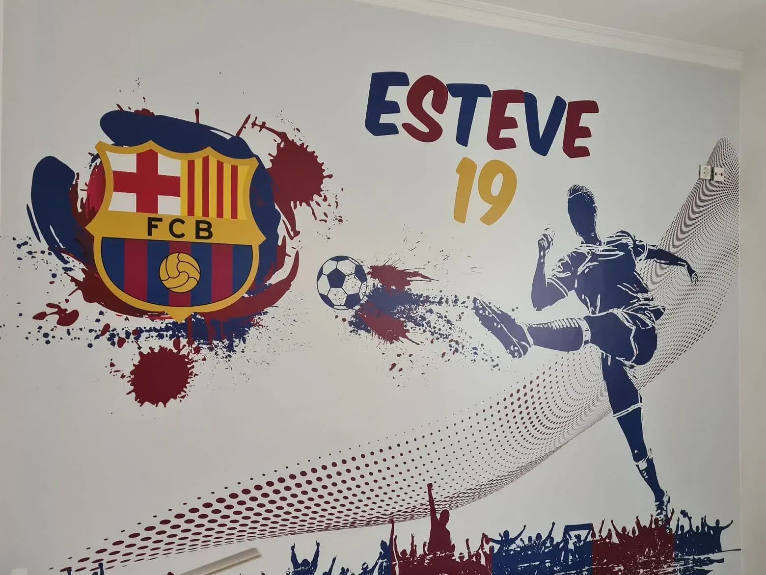 Arte mural con el logo del FC Barcelona, el nombre "ESTEVE 19" y un futbolista pateando un balón. Salpicaduras de pintura azul, roja y amarilla.