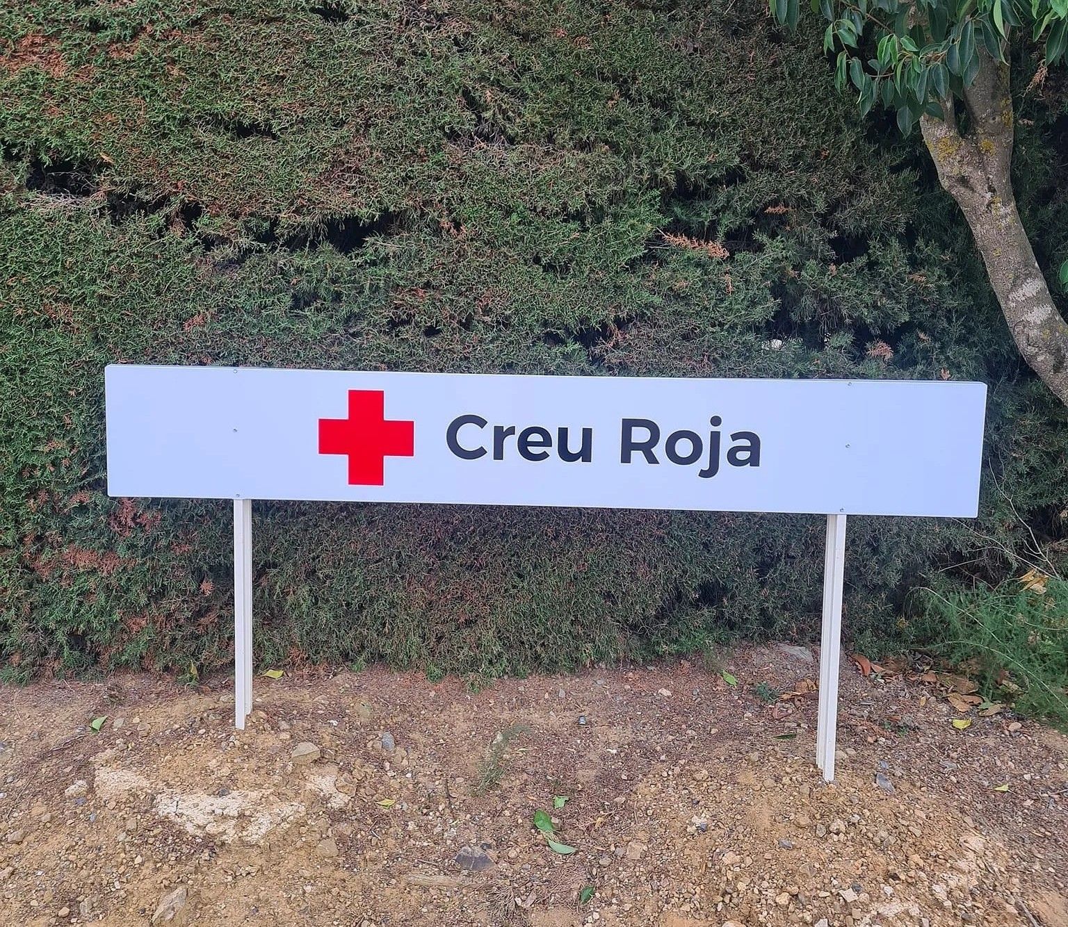 Cartel de la Creu Roja con el símbolo de la cruz roja sobre fondo verde.