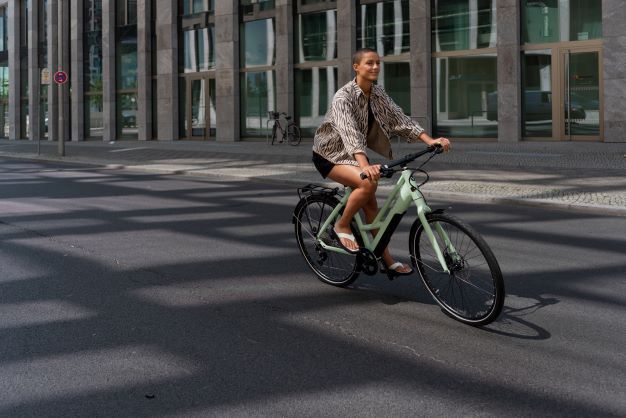 Femme roulant avec un vélo en ville sur la route