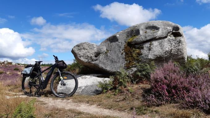 Vélo avec panier devant posé à côté d'un gros rocher